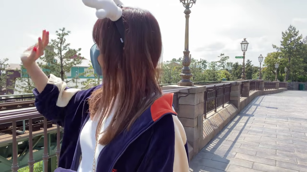 - 街並みを背景に手を振る女性