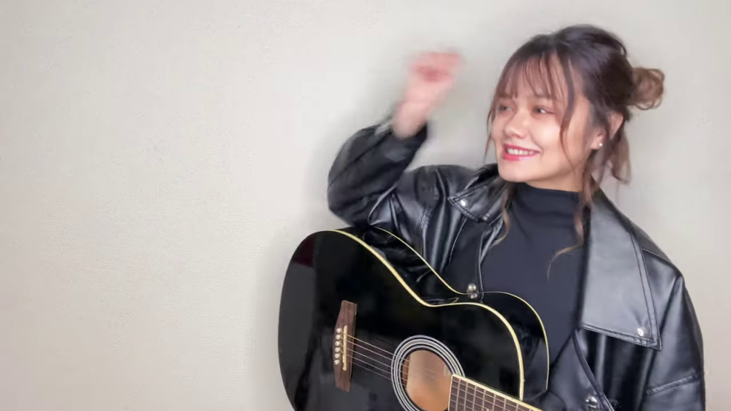明るい笑顔でギターを演奏する女性パフォーマー