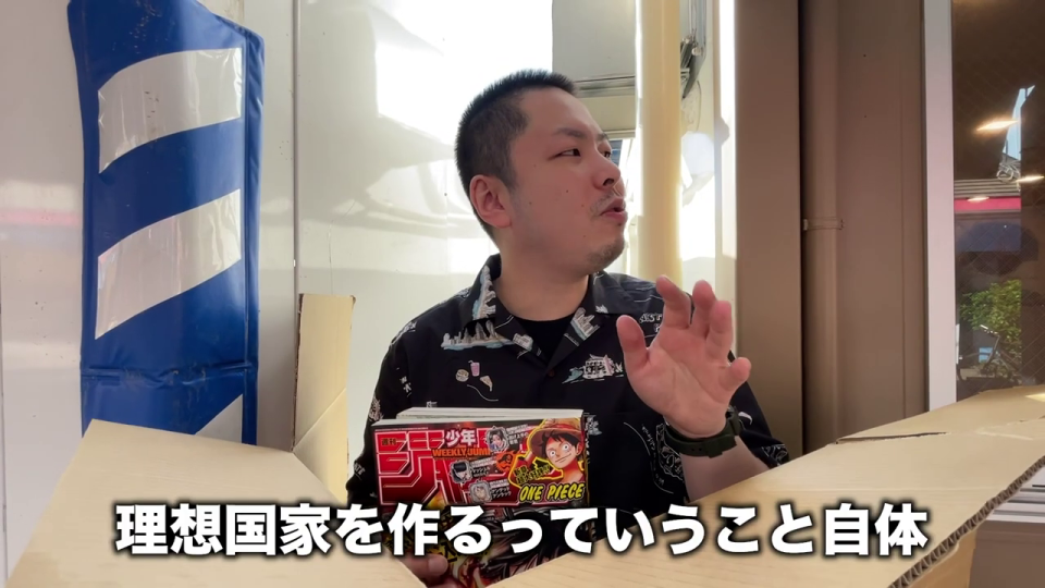 漫画を手に「理想国家」について力説する男性