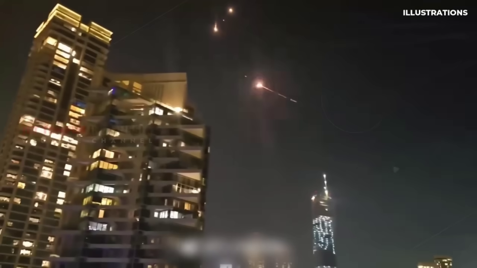 夜空に光る物体が飛行する高層ビル群の都市景観