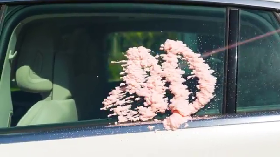 車に吹き付けられるピンク色の泡