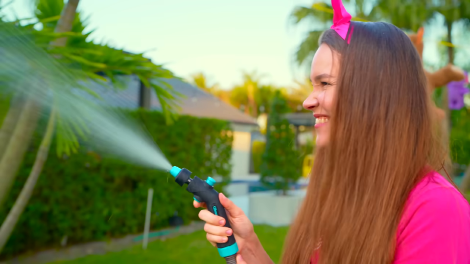 ホースで水を撒きながら笑顔の女性